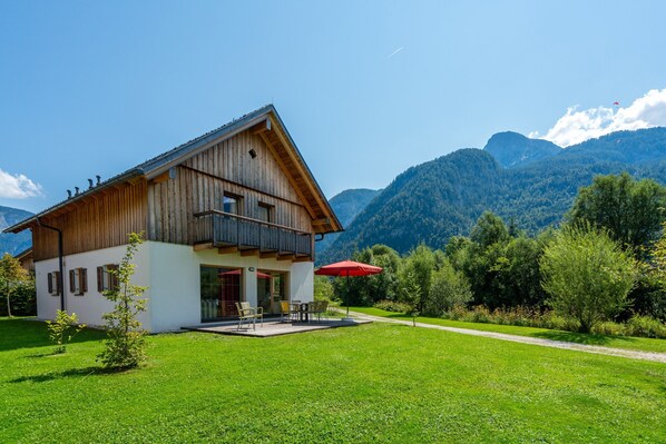 A wooden chalet with a balcony, a patio with outdoor furniture, and a mountain backdrop. - Chalet in Obertraun Near Krippenstein Ski Area (Obertraun)