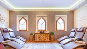 A spa room with three massage chairs, a wooden log display, and three windows with wooden frames. - Apartment in Kleinarl Near Ski Slopes (Kleinarl)