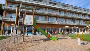 Ein mehrstöckiges Gebäude mit Balkonen, einem Spielplatz und Außenmöbeln.