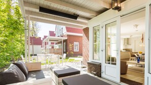 A covered patio area with outdoor seating, a brick wall, and a view into the house. - Villa in Dishoek Near Noordzee Beach (Koudekerke)
