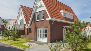 A modern two-story house with a red-tiled roof, brick exterior, and white trim. - Villa in Dishoek Near Noordzee Beach (Koudekerke)