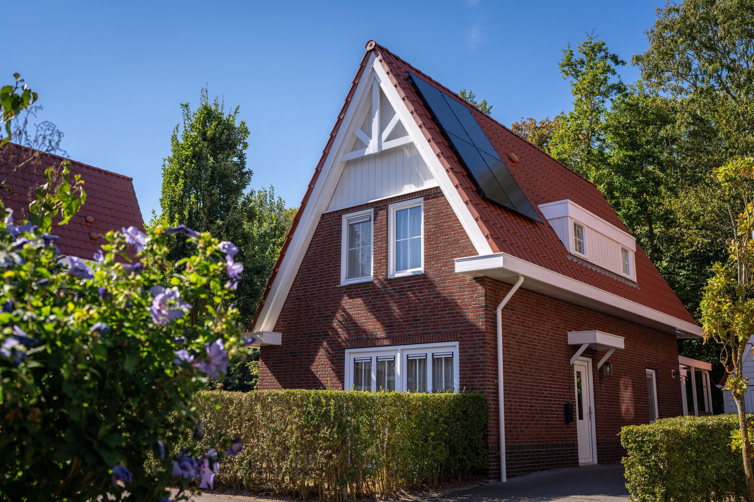 A two-story house with a red brick exterior, white trim, and a sloped roof.