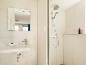Et moderne badeværelse med hvid vask, spejl og bruseniche.