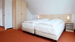 Une chambre à coucher avec un grand lit, une armoire et une table de chevet avec une lampe.
