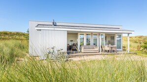 Une maison moderne dotée d’un porche abrité, d’un coin repas et d’une cuisine ouverte.