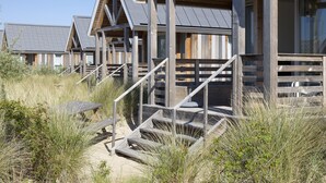 A row of wooden beach houses with external stairs leading to the entrance.