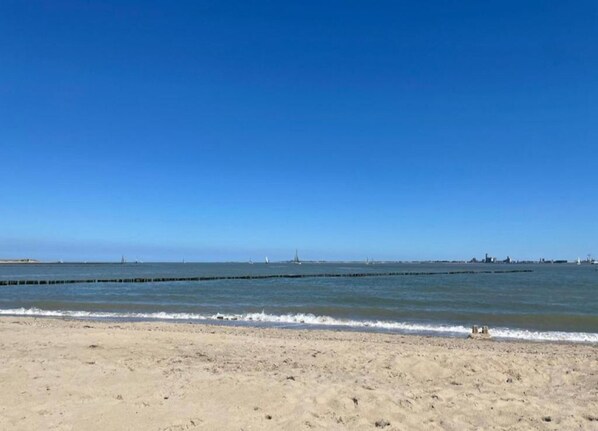 Una spiaggia sabbiosa con acque calme e un cielo azzurro limpido.