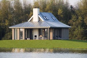 Una casa moderna con techo de metal, ventanas grandes y un césped.