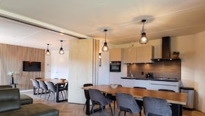 A modern living room with a sofa, a dining table with chairs, and a kitchen area with a stove and cabinets.