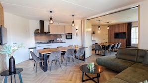 A modern living room with a sofa, coffee table, and dining area with chairs.
