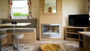 A modern living room with a sofa, a small table, a fireplace, a television, and a window with curtains. - Apartment in Netherlands Near key Attractions (Udenhout)