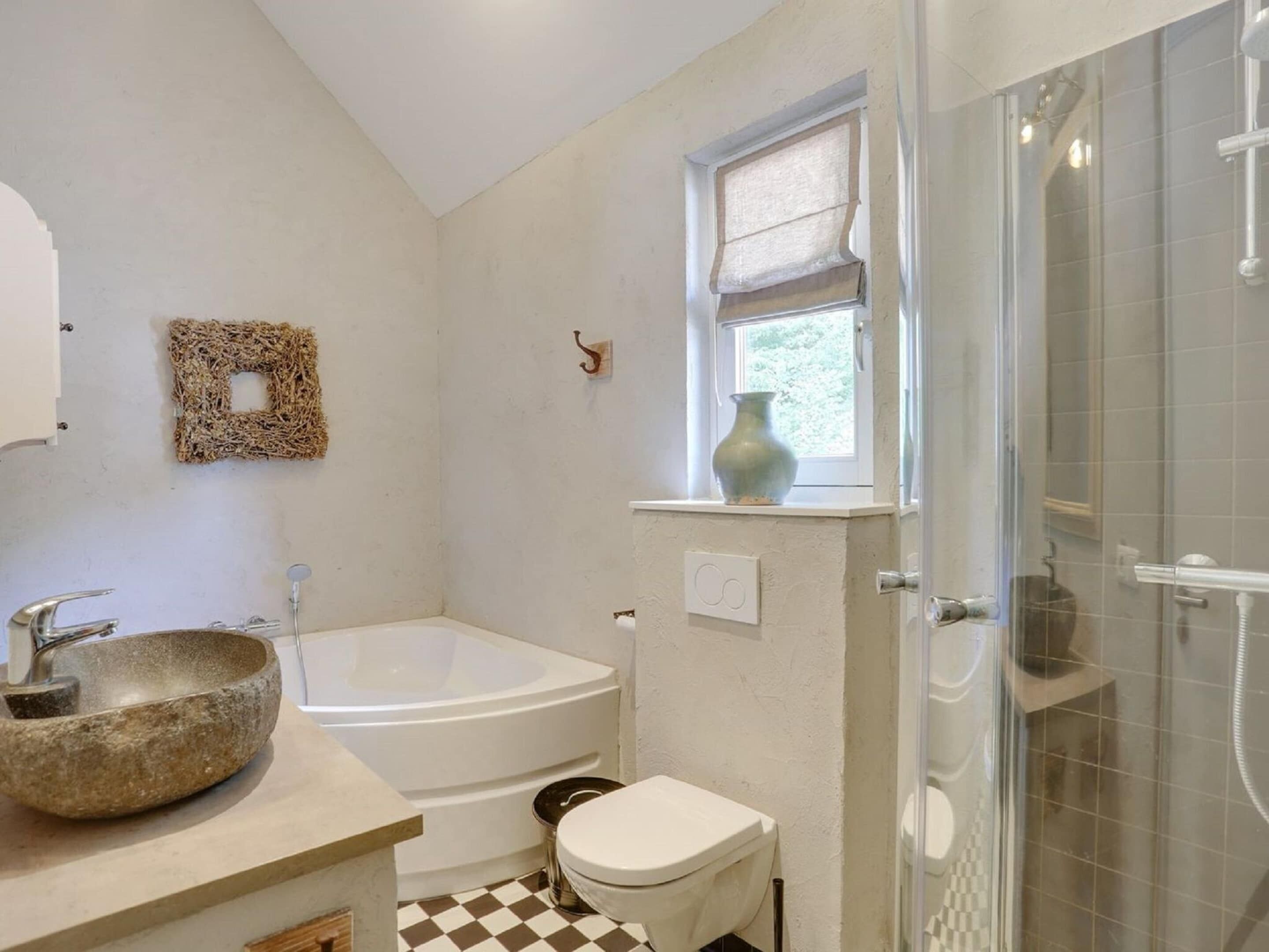 A bathroom with a stone sink, a bathtub, a toilet, and a shower.