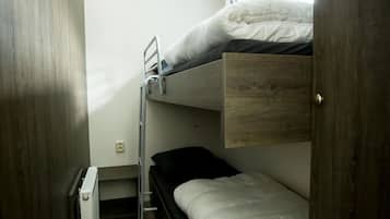 A bunk bed room with a wooden door, a small desk, and a window.