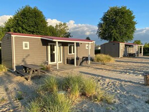 Two small, single-story cabins with attached porches, each with a bench and a table.