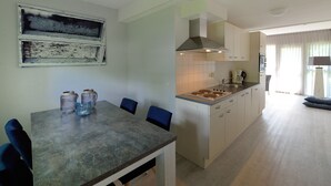 Et moderne køkken med spiseplads, med en central ø, skabe og et vindue med udsigt.