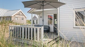 Una casa frente a la playa con porche cubierto, terraza y vista al mar.