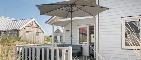 A beachfront house with a covered patio, a deck, and a view of the sea.