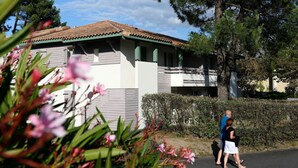 Ein Gebäude mit einem Ziegeldach, einer weißen Fassade und grünen Akzenten.