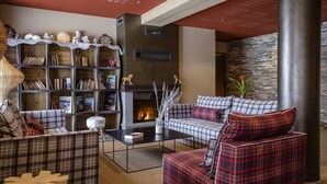 A cozy living room with a fireplace, a bookshelf, and plaid furniture. - Apartment in Beaufort With Spa & Mountain Views (Beaufort)
