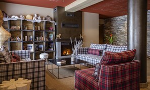 A cozy living room with a fireplace, a bookshelf, and plaid furniture. - Apartment in Beaufort With Spa & Mountain Views (Beaufort)