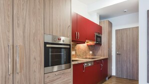 A modern kitchen with wooden cabinets, a built-in oven, and a microwave. - Apartment in Kleinarl Near Ski Slopes (Kleinarl)