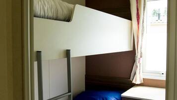 A bunk bed with a ladder, a small desk, and a window with curtains.