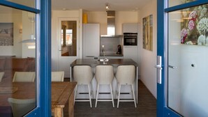 A modern kitchen with a central island, bar stools, and a dining table. - Apartment in Domburg Near Sandy Beaches (Domburg)