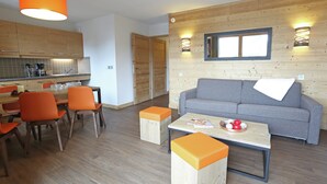 Un soggiorno moderno con un divano grigio, poltrone arancioni, un tavolino in legno e un'area pranzo in legno con poltrone arancioni.