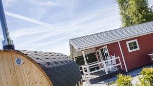 A red building with a porch and a large wooden structure with a black roof. - Chalet in Netherlands With Private Sauna (Voorthuizen)