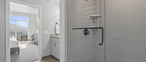 Un bagno moderno con cabina doccia in vetro, porta asciugamani e water.