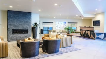 A spacious lobby with a stone fireplace, seating area, and a reception desk.