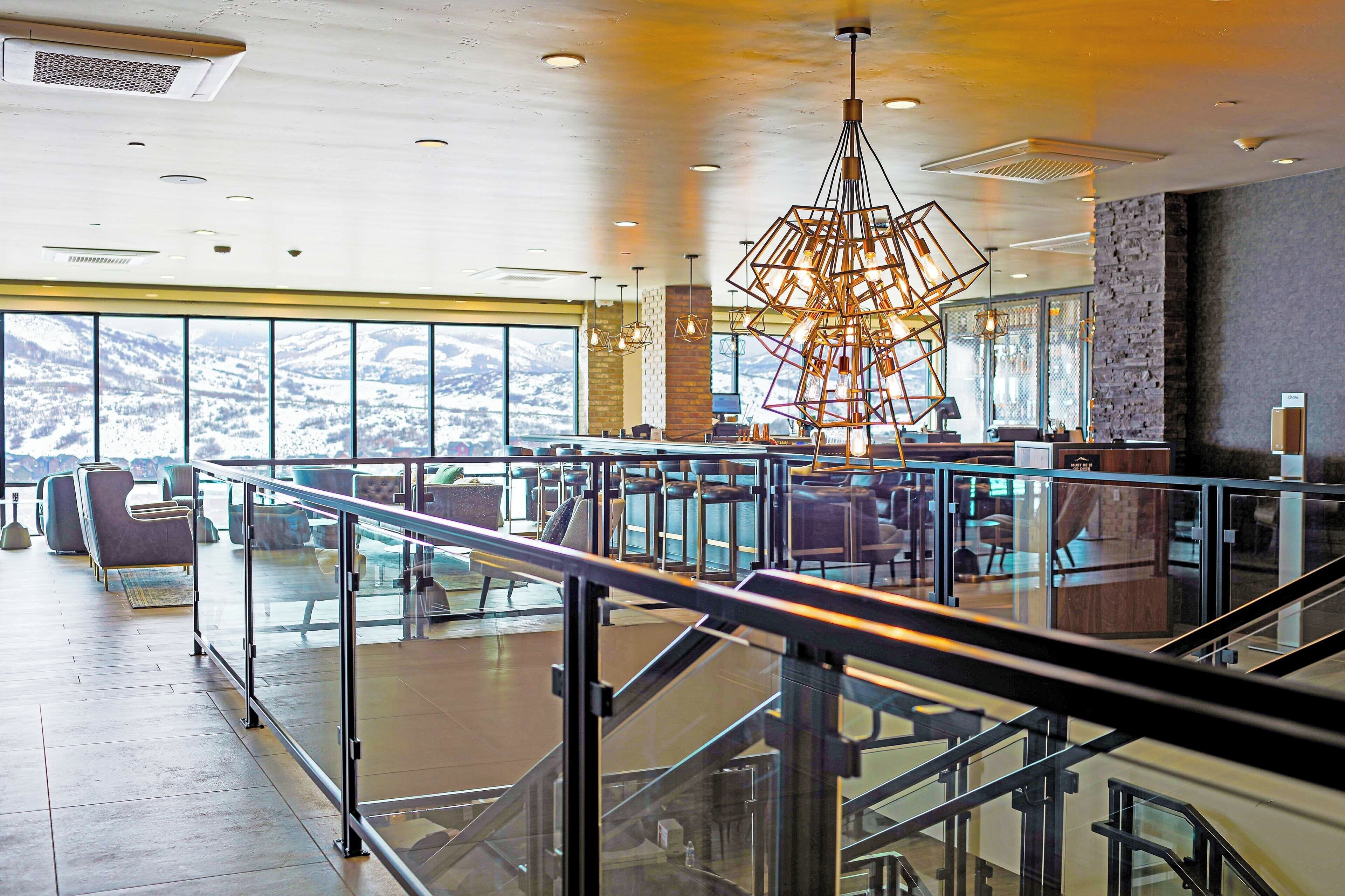 A spacious indoor area with a modern staircase, seating, and a large window offering a view of snow-covered hills.