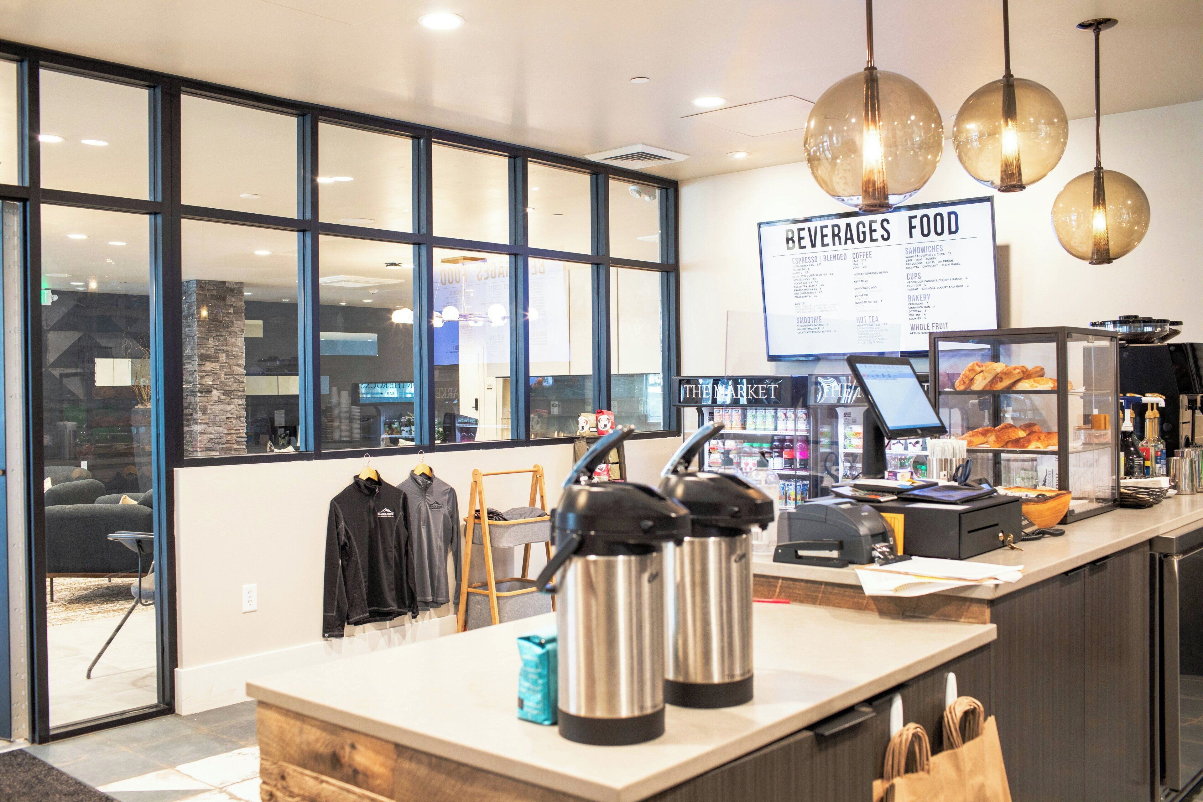 A cafe interior with a menu board, coffee machines, and a counter with pastries.