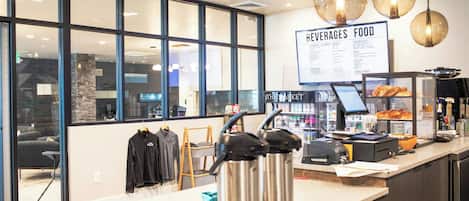 A cafe interior with a menu board, coffee machines, and a counter with pastries.
