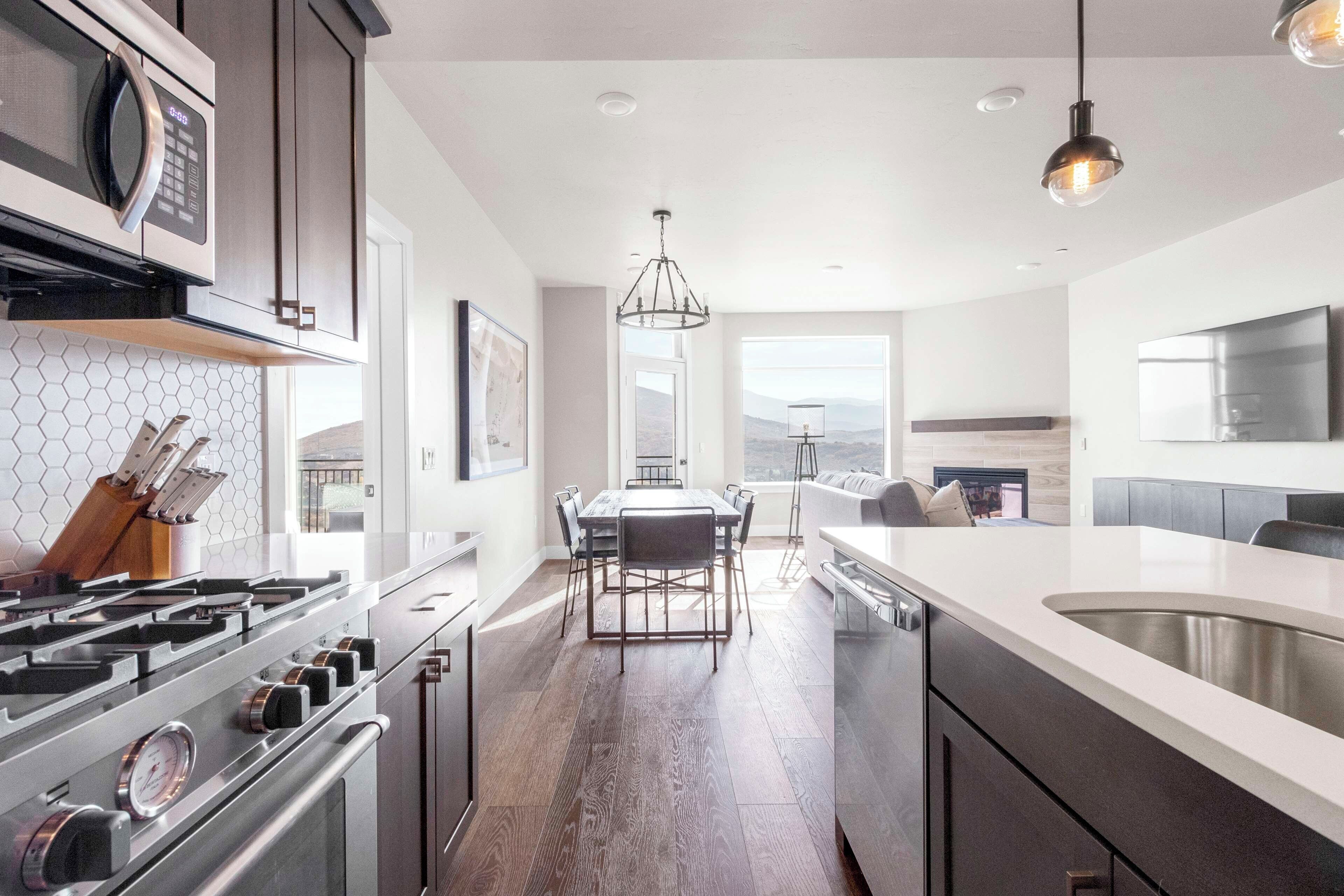 A modern kitchen with a central island, stainless steel appliances, and a dining area with a view.