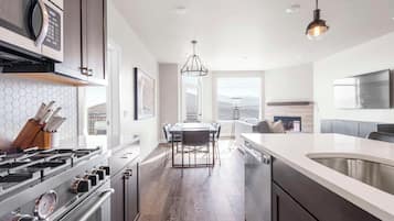 A modern kitchen with a central island, stainless steel appliances, and a dining area with a view.