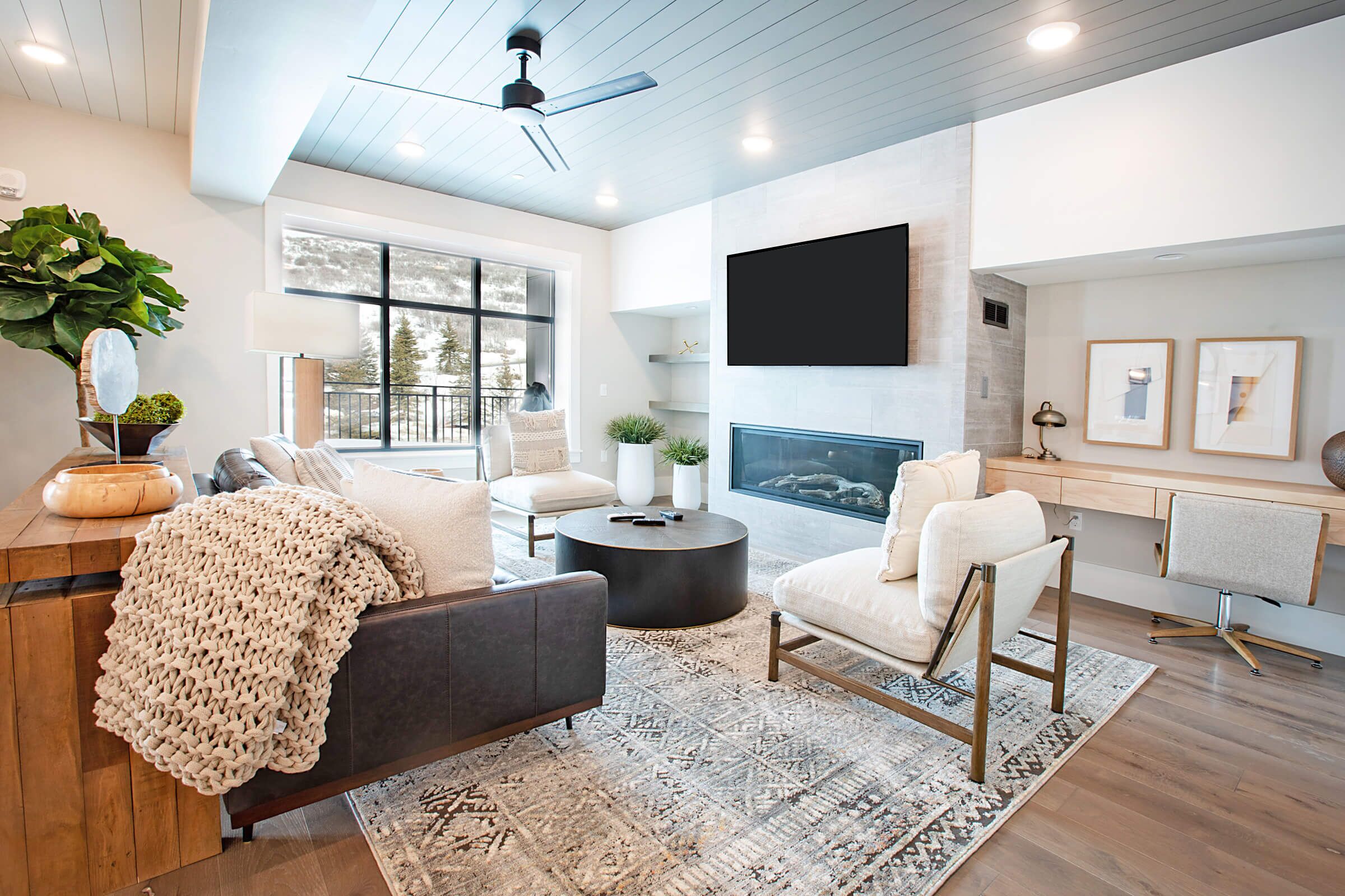 A modern living room with a sofa, armchairs, a coffee table, and a fireplace.