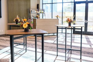 Een hotel lobby met twee tafels, een receptiebalie en een groot raam.