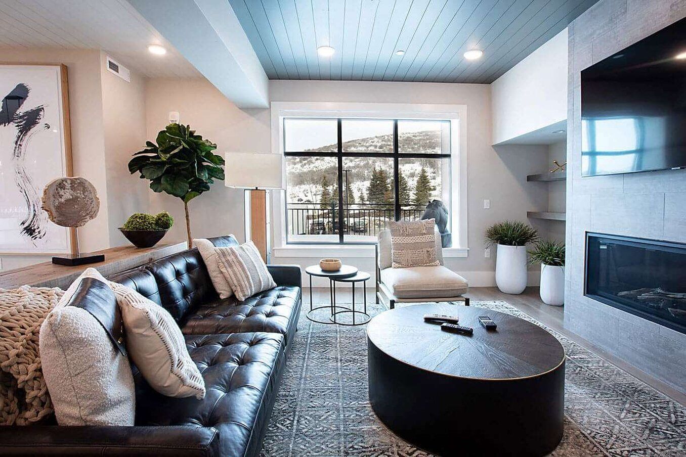 A modern living room with a leather sofa, round coffee table, and a fireplace.