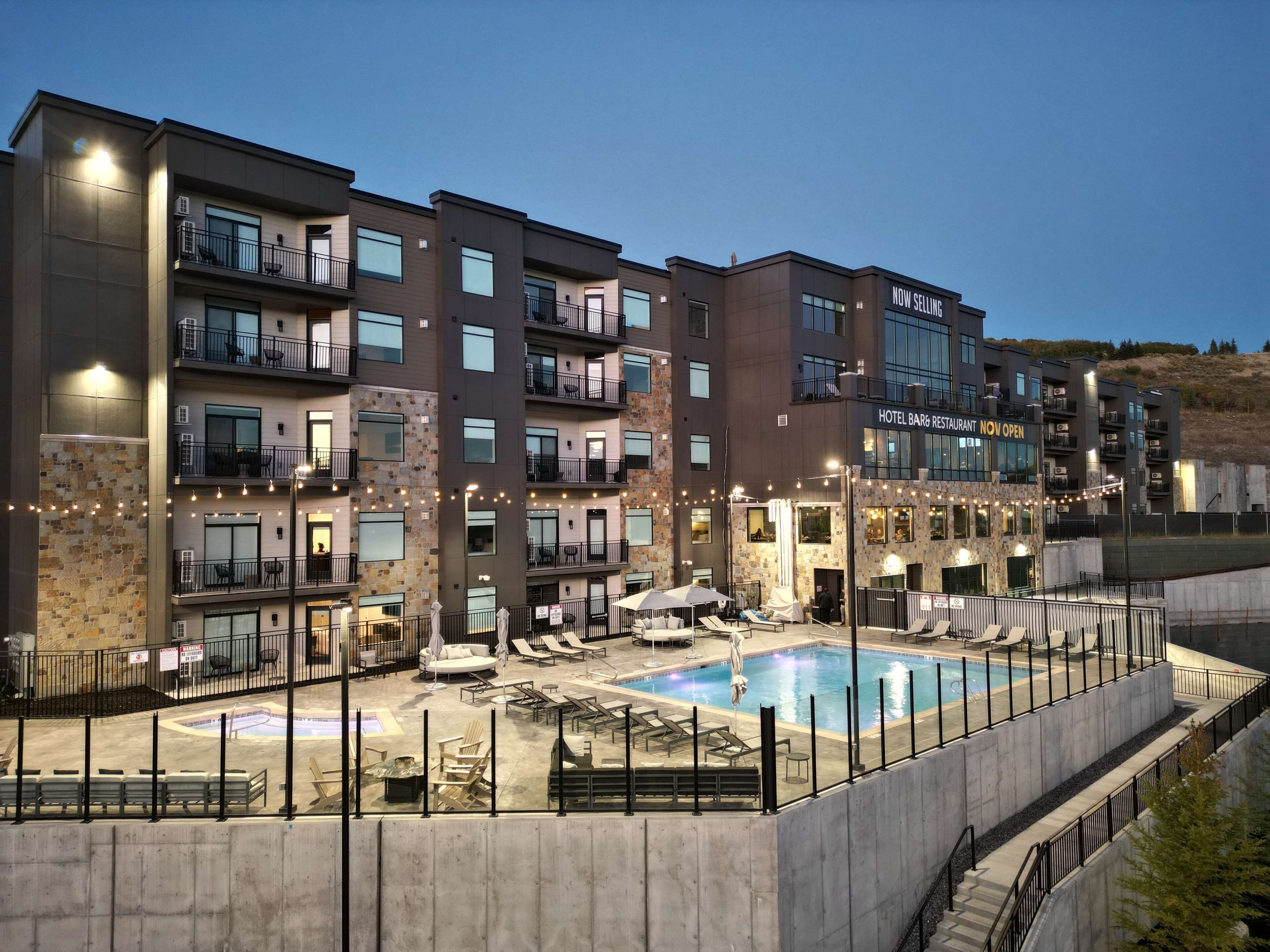 A multi-story hotel with balconies, a swimming pool, and outdoor seating.