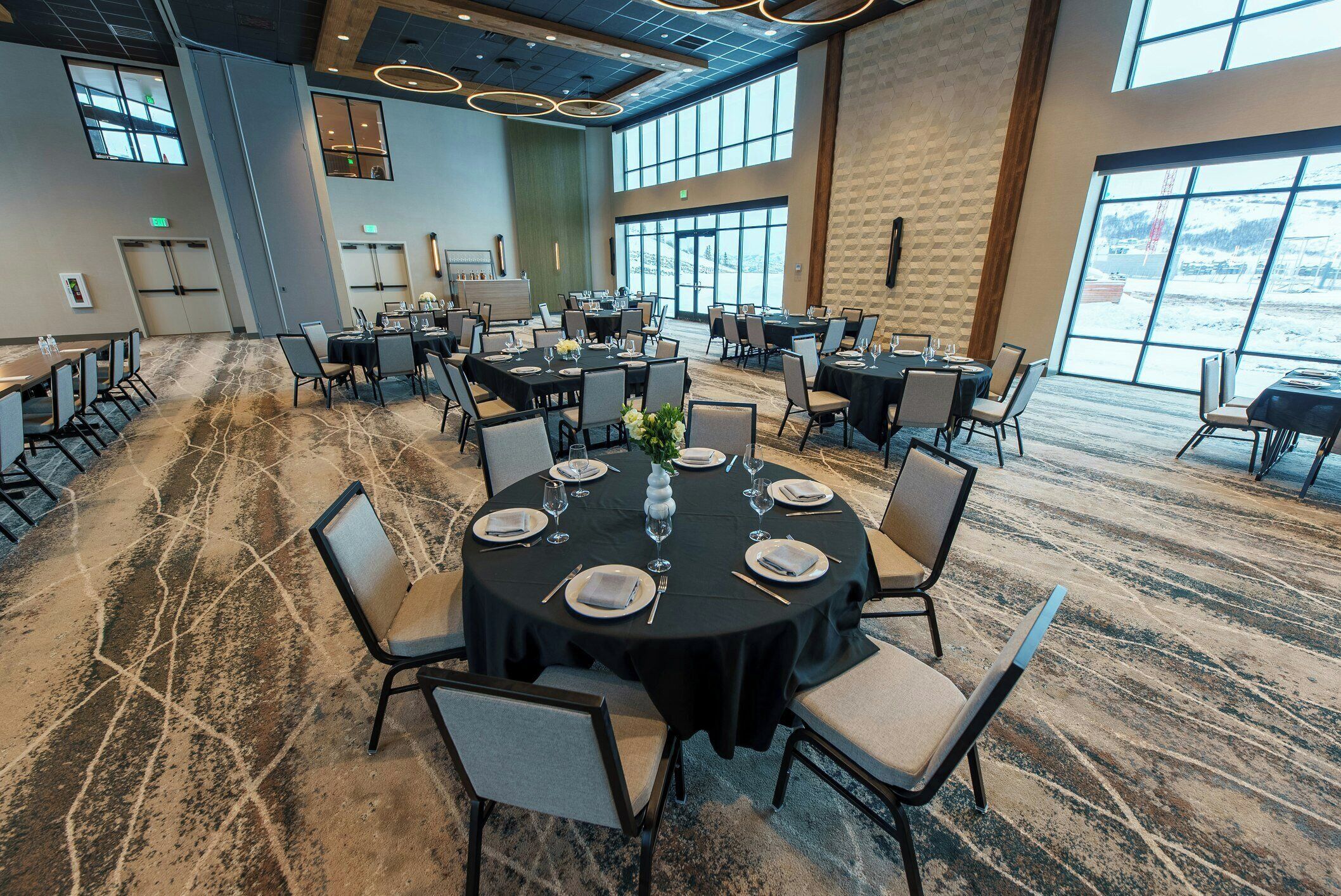 A conference room with round tables, chairs, and a carpeted floor.