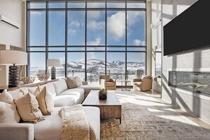 A spacious living room with a large window offering a mountain view, a fireplace, and comfortable seating. - Black Rock Mountain Resort (Heber City)