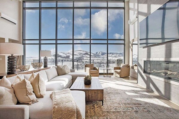 A spacious living room with a large window offering a mountain view, a fireplace, and a cozy seating area.