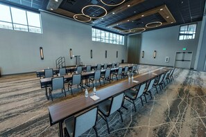 A conference room with long tables, chairs, and water bottles, featuring a modern design with a large window and a patterned carpet. - Black Rock Mountain Resort (Heber City)