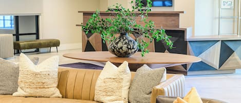 Una sala de estar moderna con un sofá, una mesa de centro y una planta decorativa en un florero.