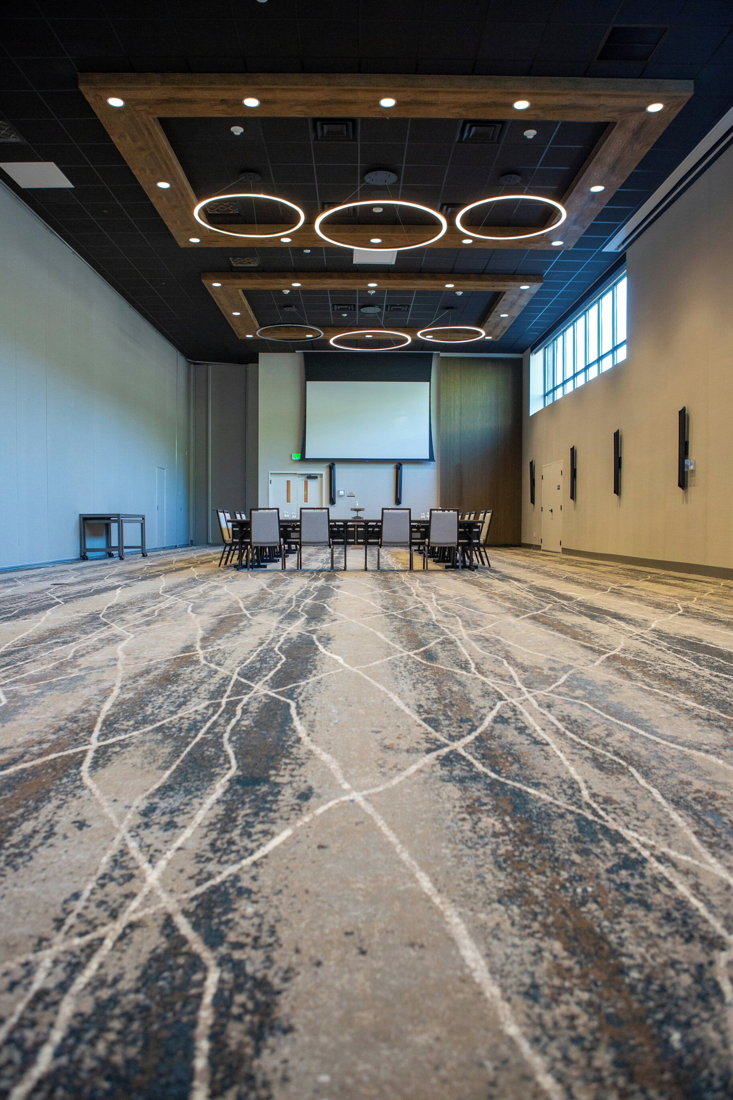 A conference room with a large screen, a projector, and a table with chairs.