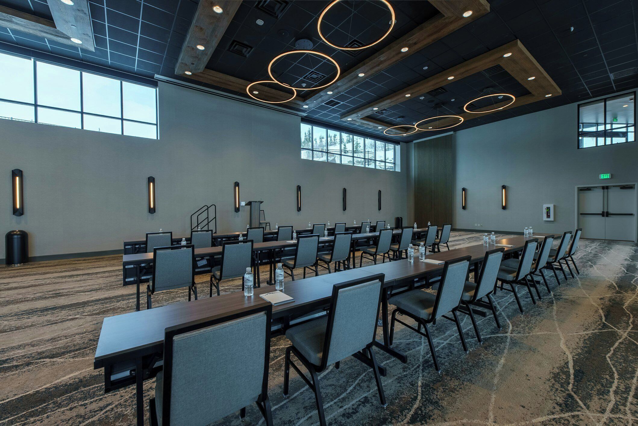 A conference room with long tables, chairs, and a carpeted floor.