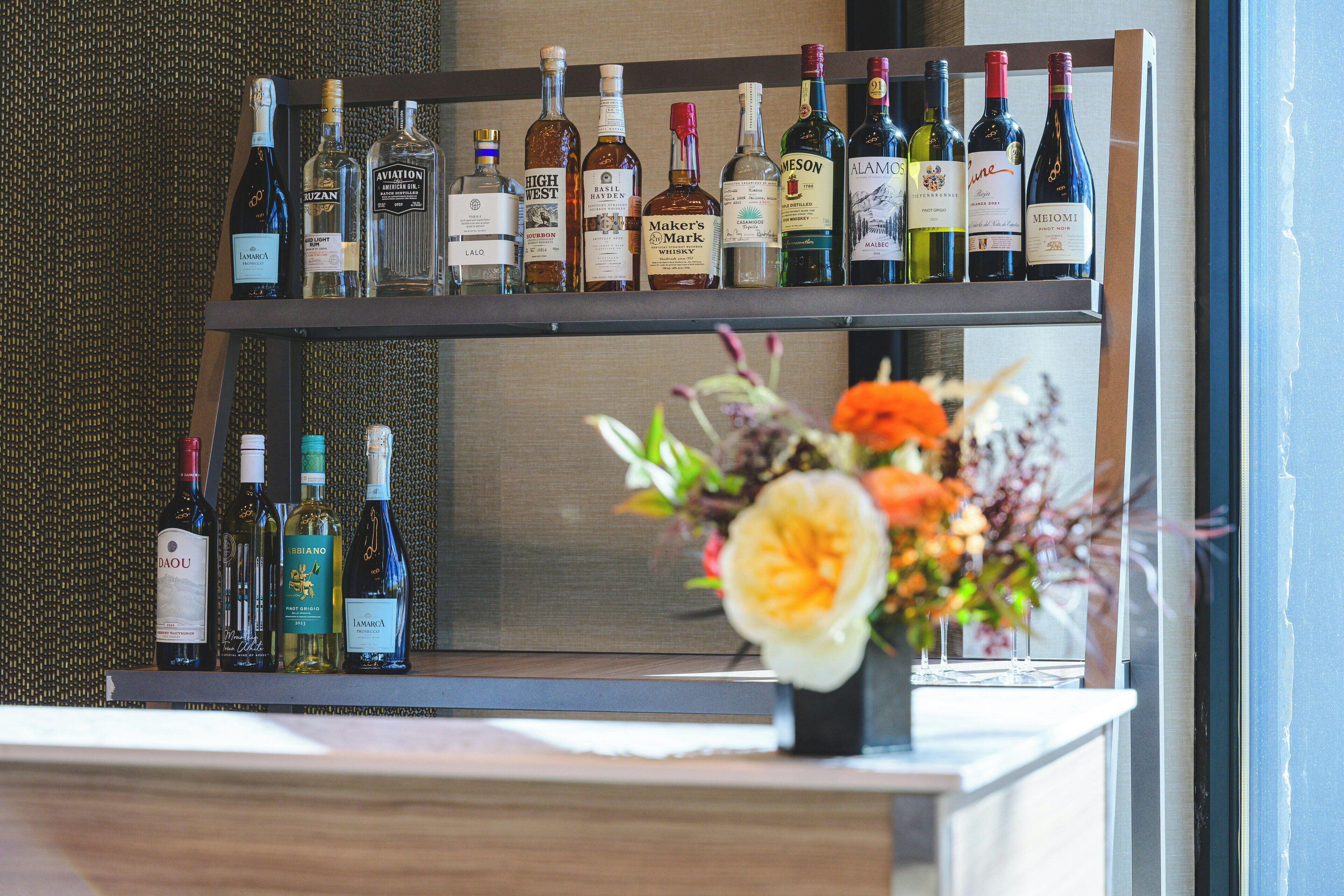 A wine rack with various bottles and a vase with flowers on a counter.