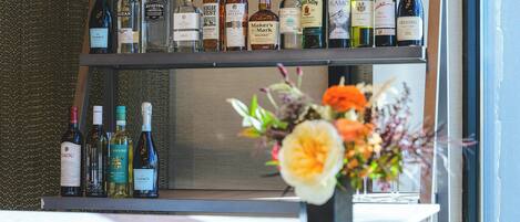 Una estantería para vinos con varias botellas y un florero con flores sobre una encimera.