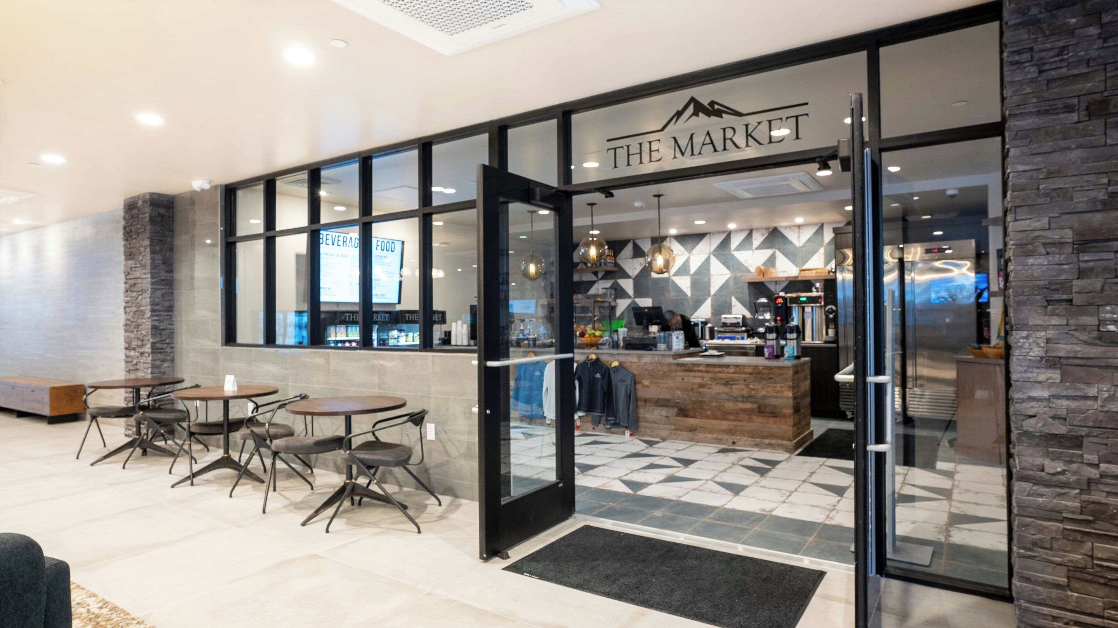 A modern cafe with a stone facade, glass entrance, and a counter with a coffee machine.